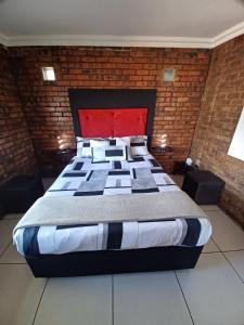 a large bed in a room with a brick wall at Duncan Garden Cottage in Brakpan