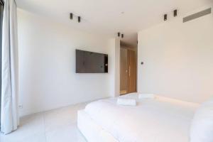 a white bedroom with a bed and a flat screen tv at Hotel Monte Sereno in Zonza