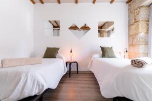 two beds in a room with white walls and wooden floors at Casa Bubela- Vía de la plata in Dozón