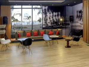 a living room with a couch and tables and chairs at ibis Jatai Shopping in Jataí
