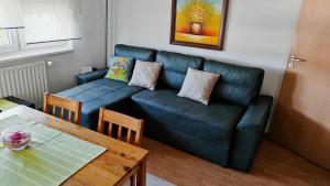 a living room with a blue couch and a table at Maslačak, dvosobni in Banja Koviljača +12 photos