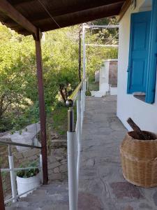 a porch of a house with a blue door and a basket at Mama's home in Arethousa