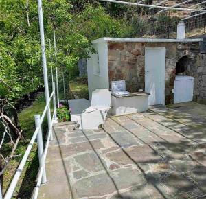a stone patio with a white chair and a laptop at Mama's home in Arethousa