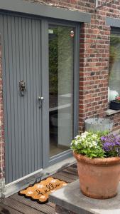a porch with a pot of flowers next to a door at Countryside house by Pairi Daiza in Silly