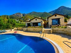 a swimming pool in front of a house with mountains at Bellapais Stone Villa in Kyrenia
