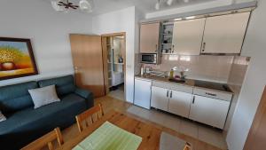 a living room with a blue couch and a kitchen at Maslačak, dvosobni in Banja Koviljača