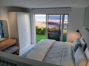 a bedroom with a bed and a large window at Hermanus Oceanbay View in Hermanus