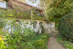 an old house with a thatched roof with a gate at Kastanienhof Strandhafer in Wisch