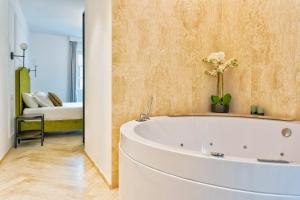 a white bath tub in a room with a bedroom at Marmori Suites Cagliari in Cagliari