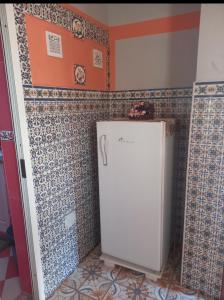 a small white refrigerator in a room with tiles at Oumayma in Sousse +1 photo