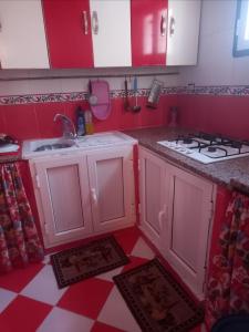 a kitchen with a sink and a stove and red cabinets at Oumayma in Sousse