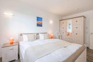 a white bedroom with a large bed and a cabinet at Ferienwohnung Haffblick in Kamminke