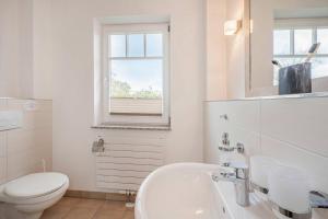 a white bathroom with a toilet and a sink at Ferienwohnung Haffblick in Kamminke +22 photos