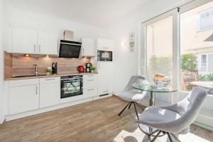 a kitchen with white cabinets and a table and chairs at Ferienhaus Kuschelnest in Kamminke