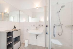 a white bathroom with a sink and a shower at Ferienhaus Kuschelnest in Kamminke +17 photos