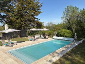 a swimming pool with chairs and umbrellas in a yard at Chateau de Briand in Luxé