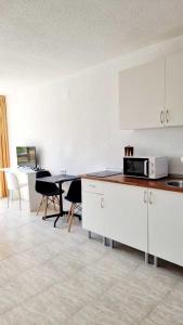 a kitchen with a microwave and a table with chairs at Pequeño estudio frente al mar, piscina y parking in Villajoyosa