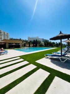 a swimming pool with lawn chairs and an umbrella at Pequeño estudio frente al mar, piscina y parking in Villajoyosa