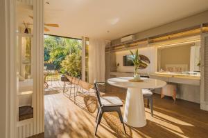 a dining room and living room with a table and chairs at Pousada Boutique Villa Valley in Praia do Rosa
