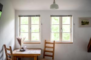 a dining room with a table and two windows at Hotel Bolter Mühle - DZ Rapskammer in Rechlin
