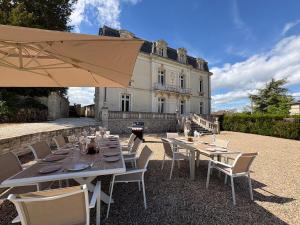 a table with chairs and an umbrella in front of a building at Chateau de Briand in Luxé