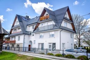 a white house with black roof at Apartamenty Przystanek Bańska in Bańska Niżna