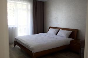 a bedroom with a bed with white sheets and a window at СічSich in Kolomiya