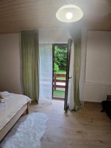 a room with a bed and a door with a window at Hanul Ibăștean in Brădeţelu