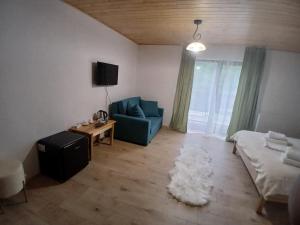 a living room with a blue couch and a rug at Hanul Ibăștean in Brădeţelu