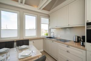 a kitchen with white cabinets and a table with chairs at Silwai OG in Westerland