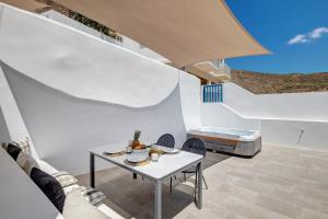 a white room with a table and chairs and a bed at Totem in Ano Syros