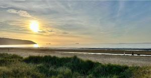 people walking on the beach at the sunset at Stunning coastal cottage in Worle