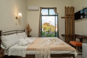 ein Schlafzimmer mit einem Bett, Handtüchern und einem Fenster in der Unterkunft Orfeas Hotel in Mytilini