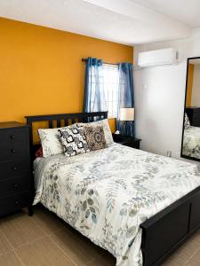 a bedroom with a bed and a yellow wall at Eden Apartments in Basseterre