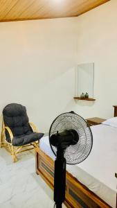 a bedroom with a fan and a chair at Mayon villa in Midigama East