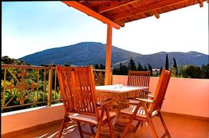a wooden table and chairs on a balcony with mountains at Anavissos pool appartment in Anavyssos