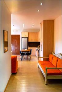 a living room with an orange couch and a kitchen at Anavissos pool appartment in Anavyssos