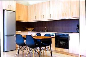 a kitchen with a wooden table and blue chairs at Anavissos pool appartment in Anavyssos +6 photos