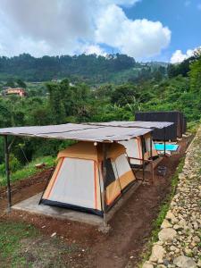 a group of tents with a roof on a hill at Cihulu Budget Glamping in Tengahgirang +32 photos