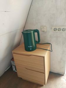 a green cup sitting on top of a wooden cabinet at Cihulu Budget Glamping in Tengahgirang