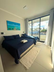 a bedroom with a blue bed and a large window at Casa 03 suites Maragogi Japaratinga in Japaratinga +61 photos