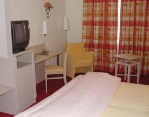 Schlafzimmer mit einem Bett, einem Schreibtisch und einem TV in der Unterkunft Gasthof zum Brunnen in Mörnsheim