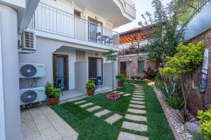 a garden with grass and plants in front of a building at Rumet Cunda Otel in Ayvalık