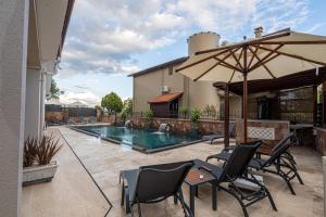 a patio with chairs and an umbrella and a pool at Rumet Cunda Otel in Ayvalık