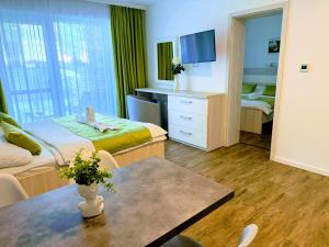 a room with two beds and a table and a tv at VILLA MEGER in Veľký Meder