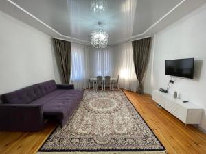 a living room with a purple couch and a tv at Guest Home in Jalal-Abad