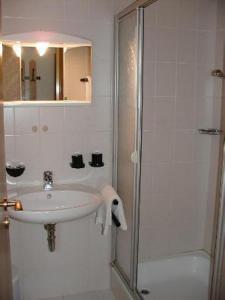 a white bathroom with a sink and a shower at Gasthof zum Brunnen in Mörnsheim
