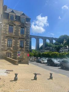a building on a street with a bridge in the background at Mur des Horizons in Plouigneau