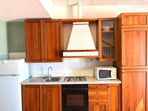 a kitchen with wooden cabinets and a stove and a microwave at Agriturismo Nani in Altavilla Monferrato