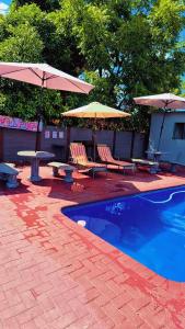 a patio with chairs and umbrellas next to a pool at Little Haven! in Rustenburg